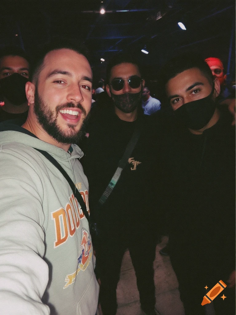 Selfie of three men, two wearing masks, at a dimly lit event.