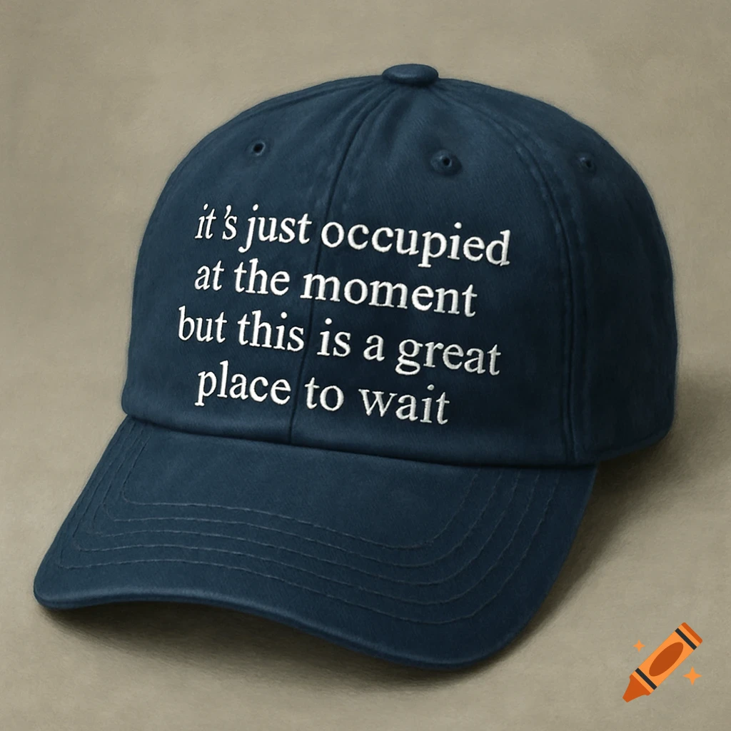 Dark blue baseball cap with white text that says 'It ’s just occupied at the moment but this is a great place to wait'