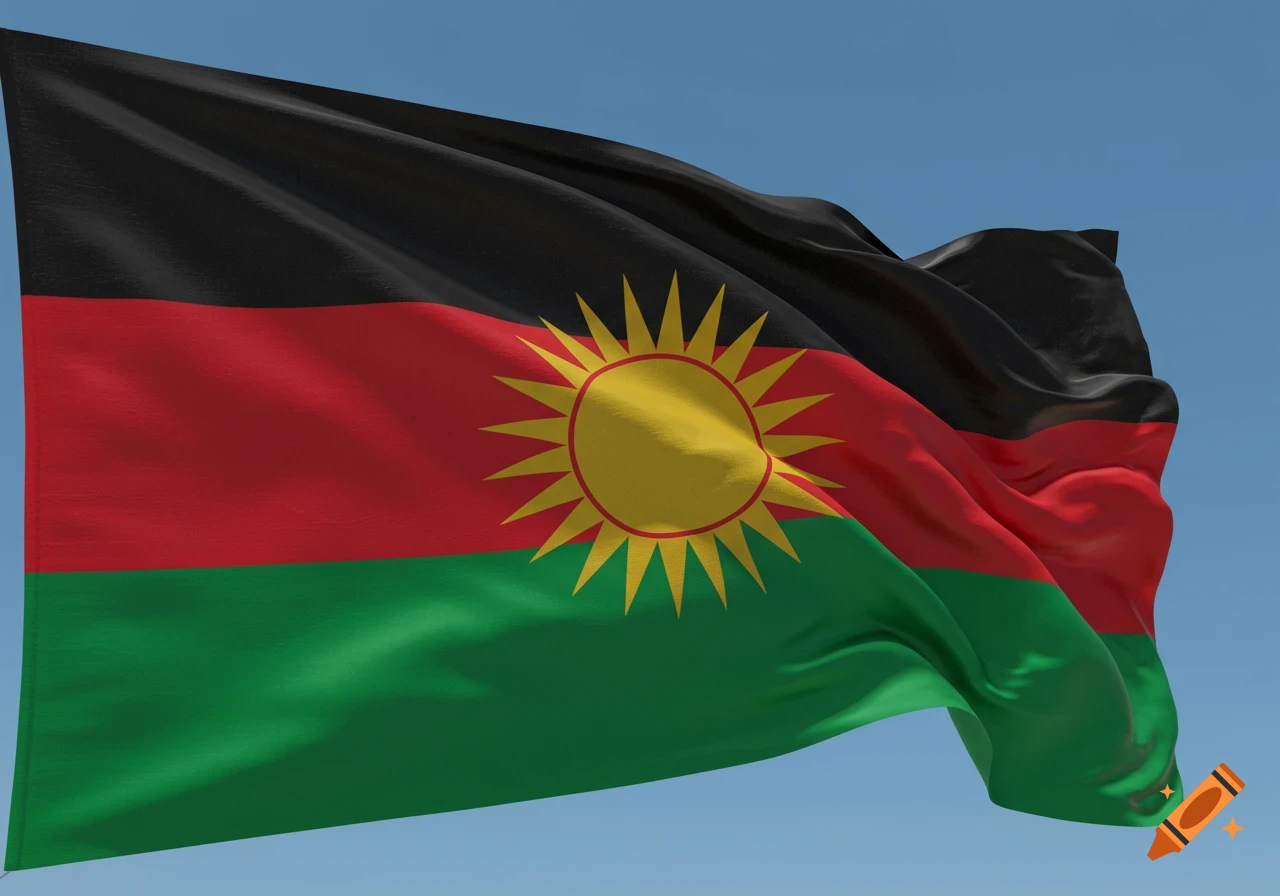 A Biafran flag with black, red, and green stripes and a yellow sun in the center waves against a clear blue sky.