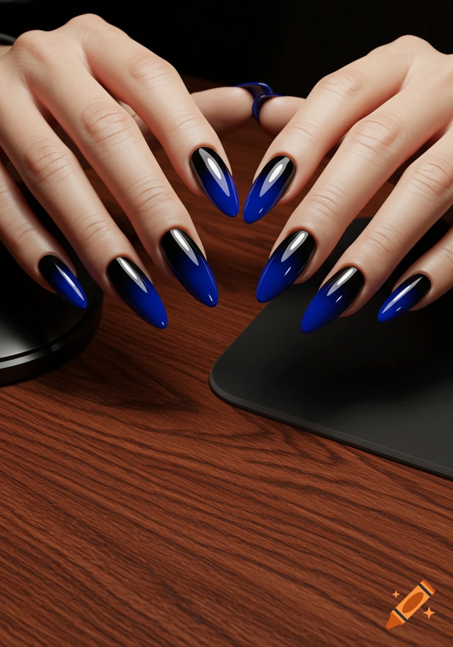 Close-up of hands with almond-shaped black and blue gradient nails on a wooden desk with a black mousepad.