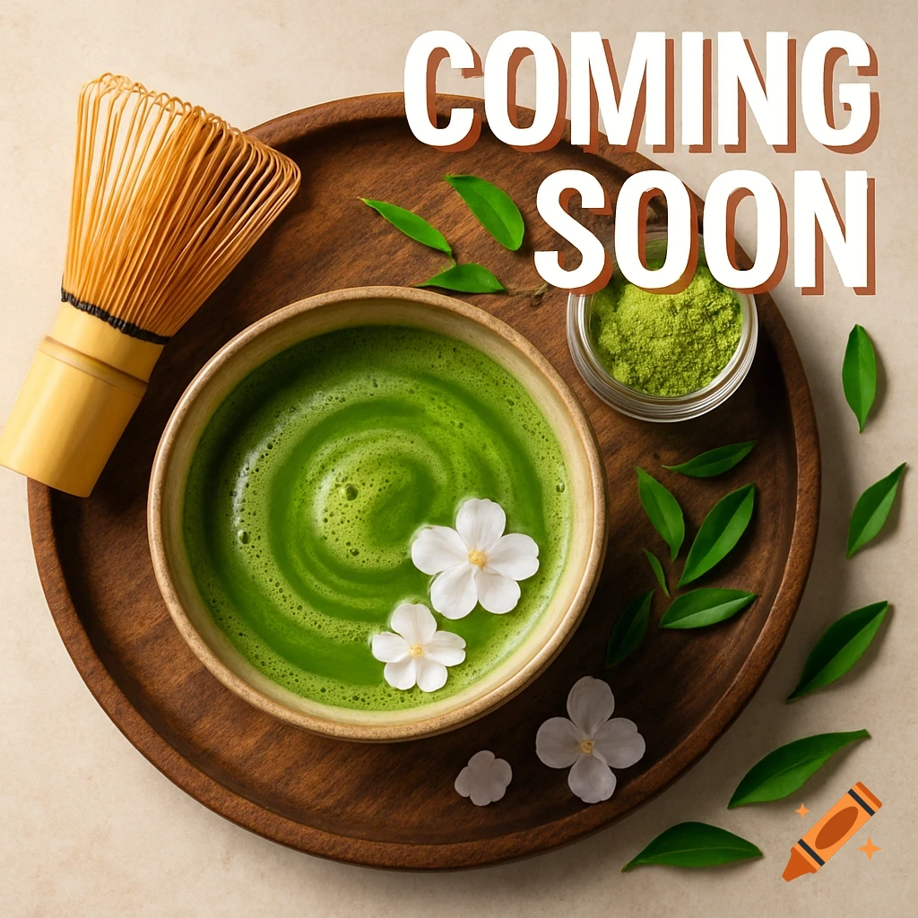 Overhead view of frothed matcha tea, whisk, powder, leaves, and white flowers on a wooden tray, with 'COMING SOON' text.