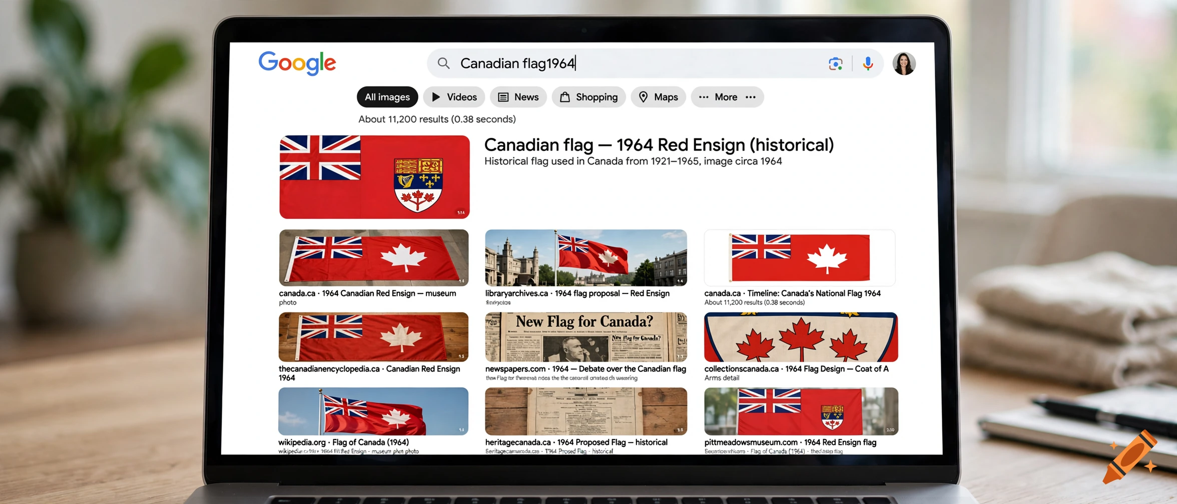 Laptop displaying a Google search results page for Canadian flag 1964 on a wooden desk.
