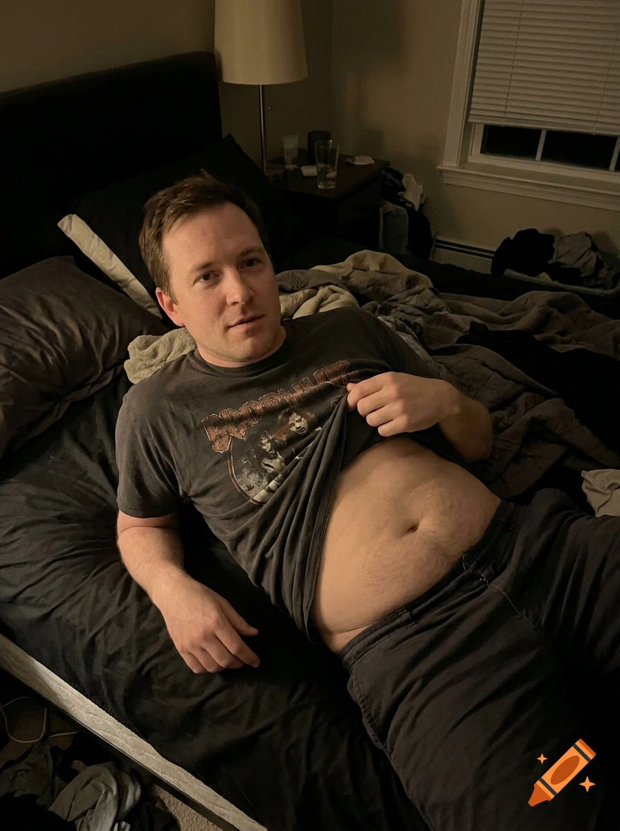 A man lying on a bed in a dim room, slightly lifting his t-shirt to reveal his stomach, photorealistic style.